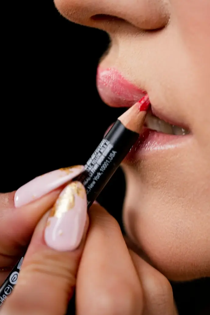 a woman putting a lip liner on her lip